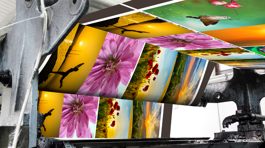 The image depicts a large industrial printer in action, producing high-quality, vibrant prints featuring various images. These images include close-up photographs of colorful flowers, sunsets, nature landscapes, and artistic silhouettes. The printer appears to be working efficiently, with prints flowing smoothly as they emerge from the machine, showcasing a range of bright, detailed, and colorful designs.